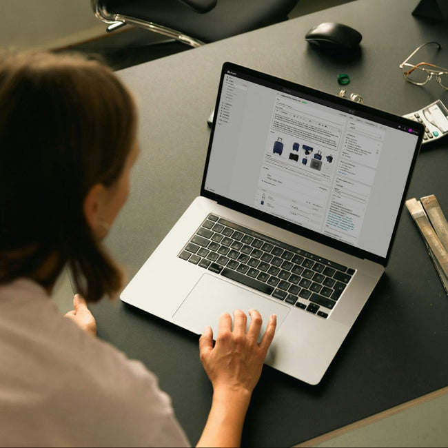 Person using a laptop with the Shopify admin panel at a desk with various items around
